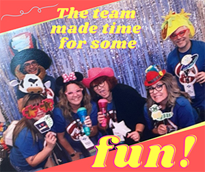 group of adults in a photobooth with funny props