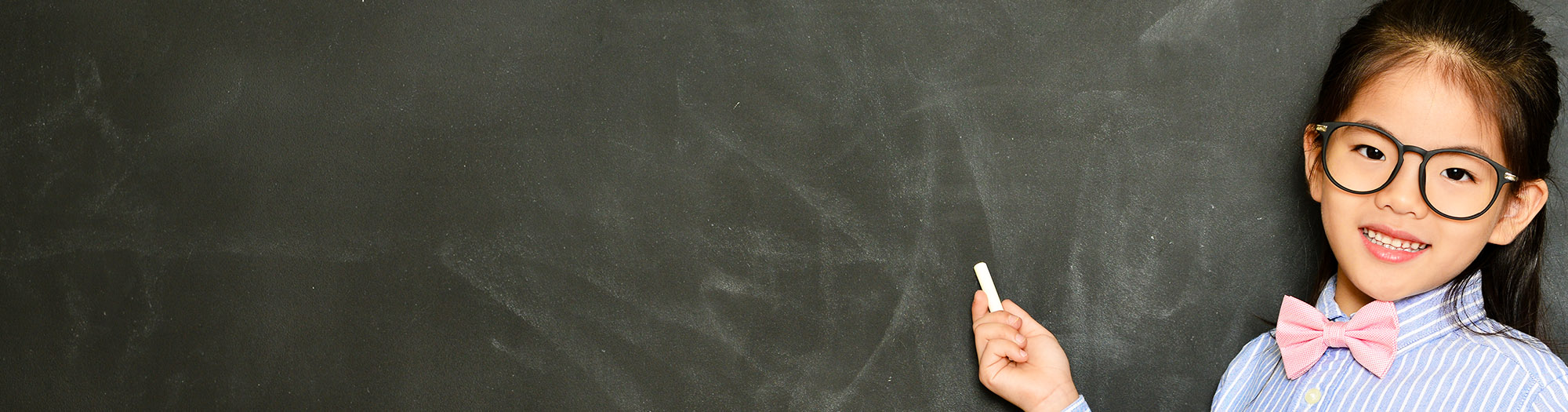 Young girl dressed as a teacher in front of chalkboard