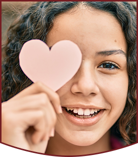 Hispanic teenager girl smiling and holding a paper heart