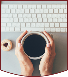 SWREC team member holding cup of coffee at desk with a hear-shaped cookie